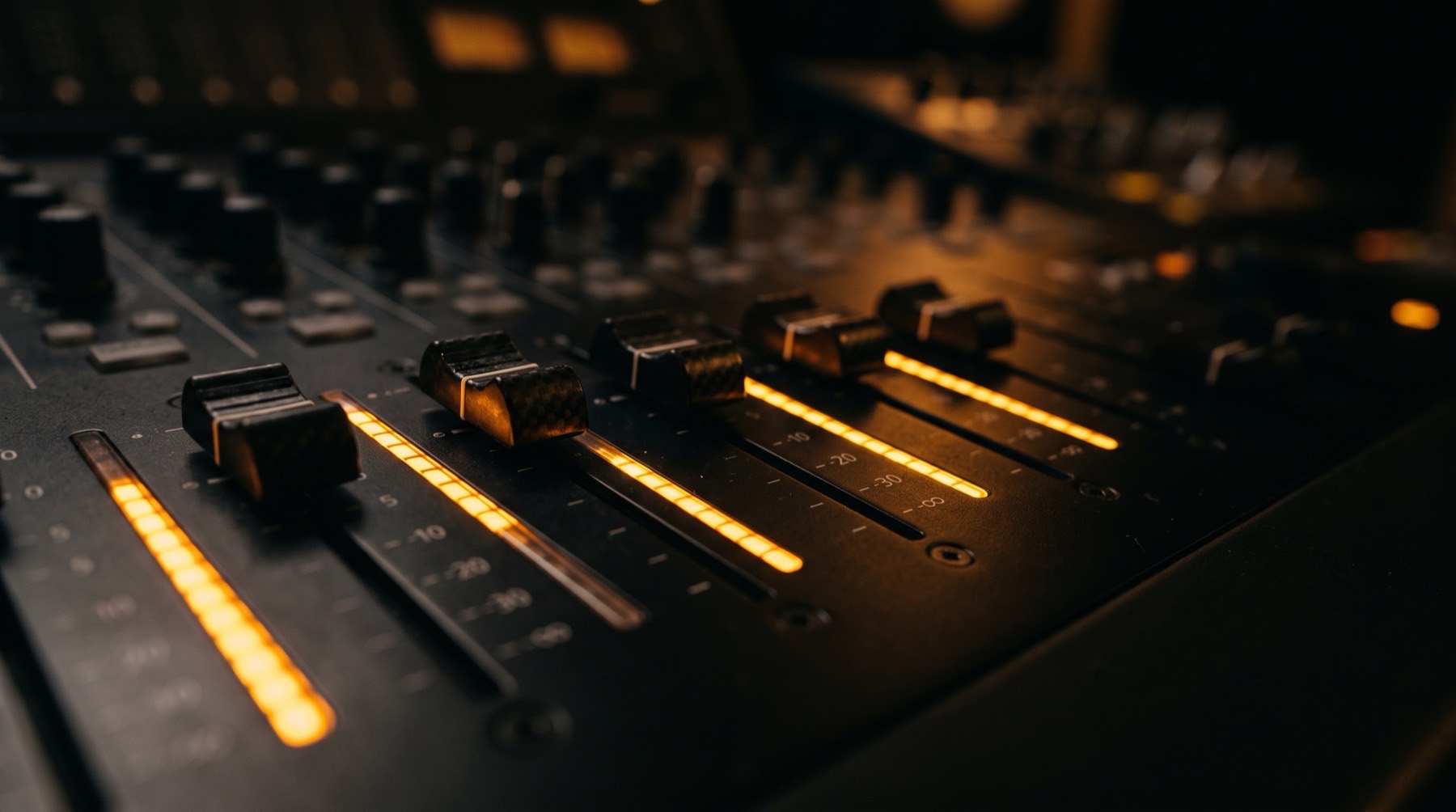 Modern mixing console faders glowing amber in a dark Los Angeles studio